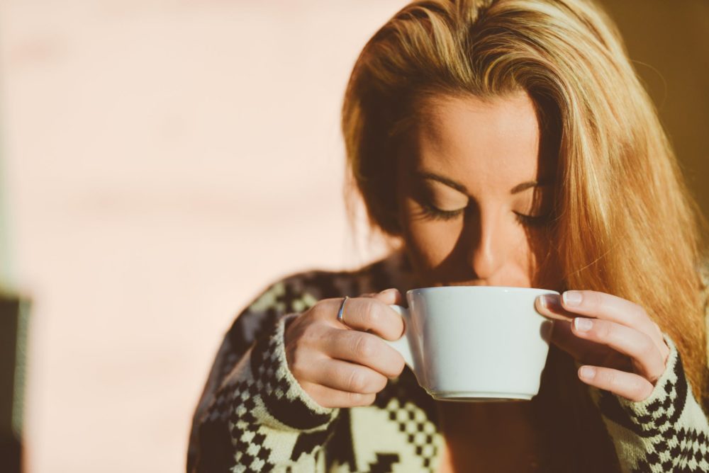 Mulher loira segurando uma xícara de chá